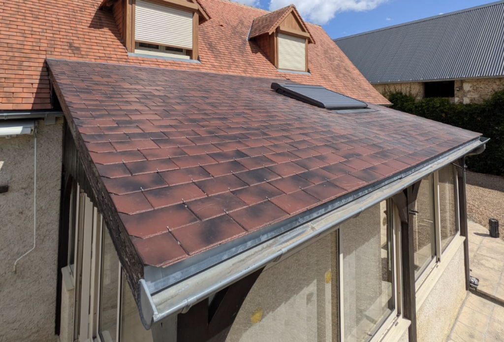 Cette finition présente des nuances qui évoluent du brun sombre vers des tonalités plus chaudes. Par conséquent, elle s’accorde naturellement avec les tuiles rouges de la toiture principale.